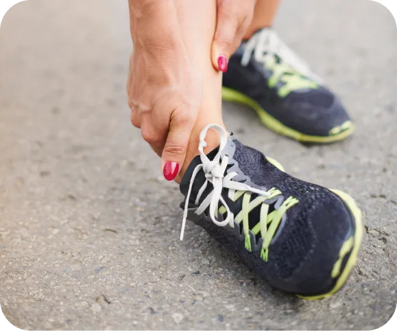 Close-up of a person holding their ankle after a sprain, illustrating pain and weakness associated with chronic lateral ankle instability