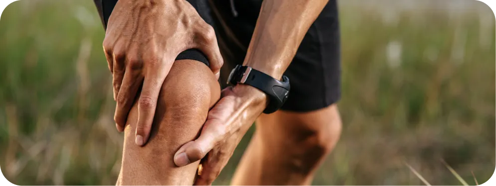 Close-up of an athlete holding the front of the knee due to pain, illustrating symptoms of chronic patellar fat pad inflammation and overuse injury