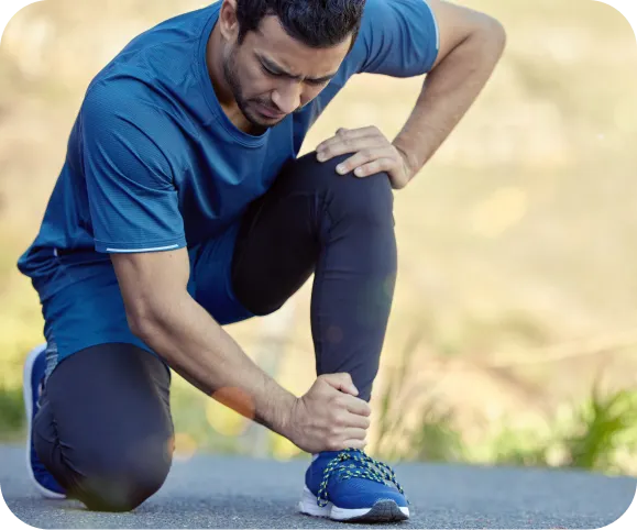 Man holding his ankle in pain after exercise, illustrating inflammation and discomfort caused by ankle synovitis or anterior ankle impingement