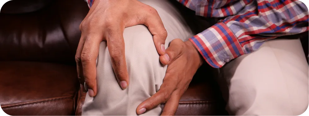 Man holding his knee in pain while sitting, showing severe joint discomfort associated with end stage osteoarthritis.