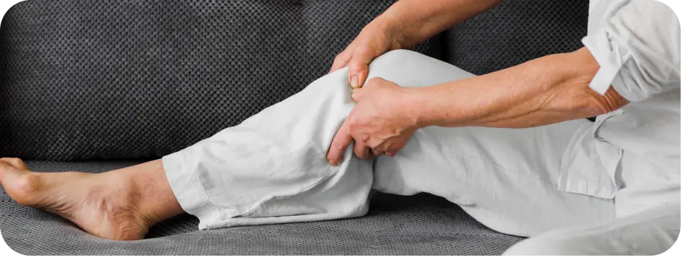 Older adult holding painful knee while seated, showing common symptoms of a meniscus tear