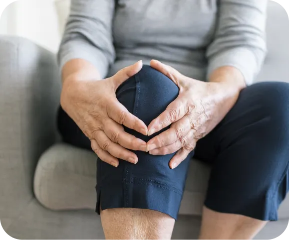 Older adult holding a swollen, painful knee, showing common symptoms of chronic synovitis and joint inflammation
