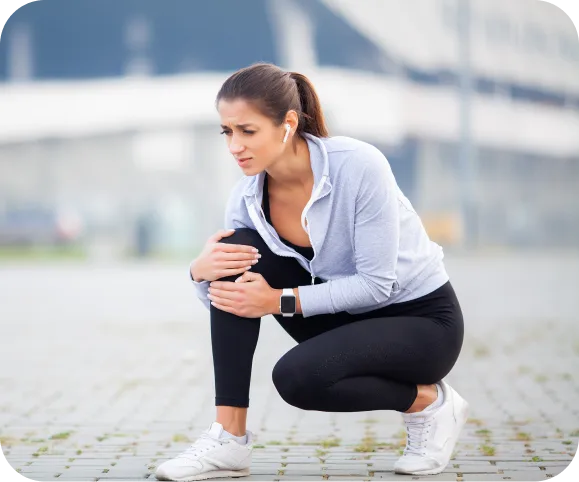 Woman holding her knee in pain after a patellar or quadriceps tendon rupture during exercise