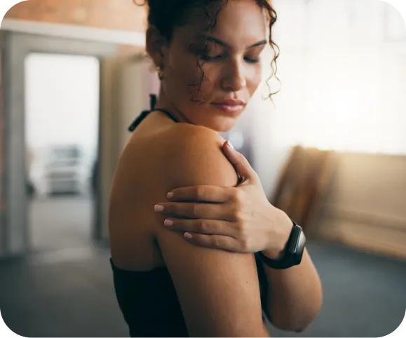 Woman touching her painful shoulder, illustrating common symptoms of a rotator cuff tear and shoulder tendon injury