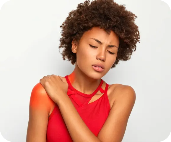 Woman holding her painful shoulder with visible discomfort, illustrating common symptoms of a clavicle (collarbone) fracture