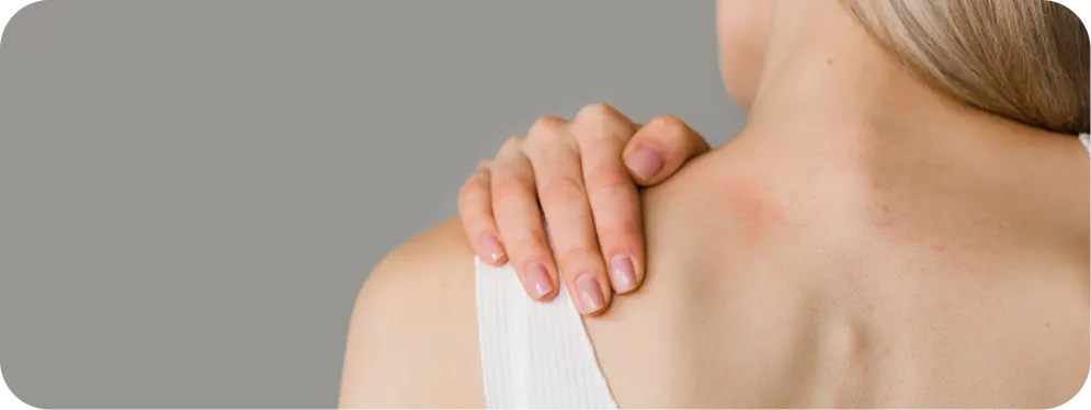 Close-up of a woman holding the top of her shoulder, showing pain and tenderness commonly linked to a clavicle fracture
