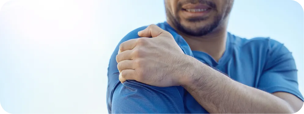 Close-up of a man holding his painful shoulder, showing symptoms commonly linked to rotator cuff tears and tendon inflammation